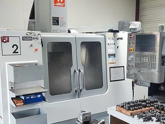 Parc machines USI64 - Tour cnc Haas TL-2 Machine CNC avec écran de contrôle, outils de précision et étagère à côté.