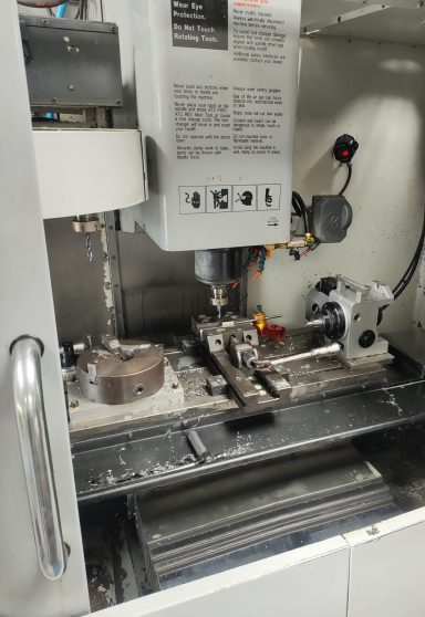 Machine de précision avec tête de fraisage et pièce en cours de fabrication.