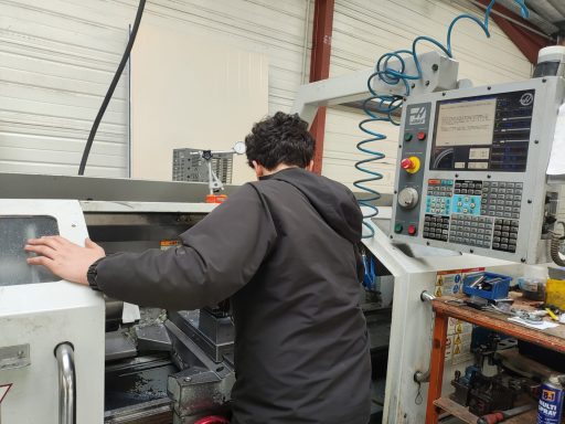 Un opérateur travaille sur une machine-outil à commande numérique en atelier.