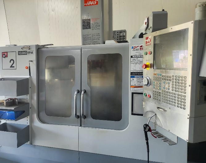 Machine-outil CNC avec écran de commande et panneaux de contrôle à l'avant.