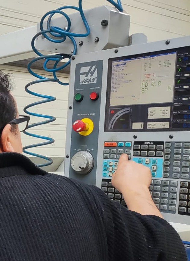 Un opérateur utilisant un panneau de commande CNC avec divers boutons et un écran.